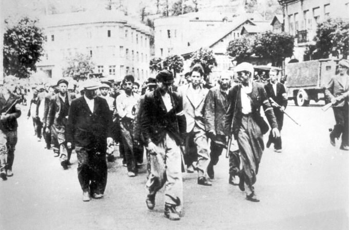 Deportation of Jews across George Maciunas Square under the guard of armed Lithuanians, in the background the Chamber of Agriculture of the Republic of Lithuania (left), June 1941