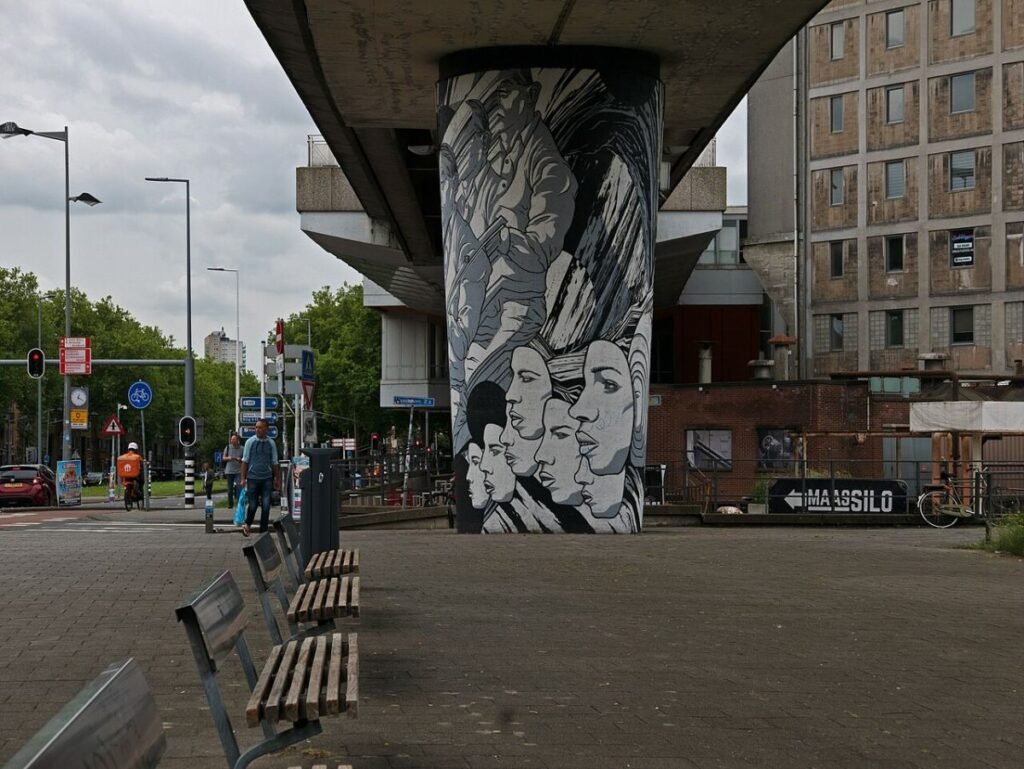 2024 - free download photo Rotterdam, the metro viaduct track with a huge concrete column, painted as street art mural of faces; location is the metro stop Maashaven Zuidzijde; Dutch street photography Fons Heijnsbroek, The Netherlands